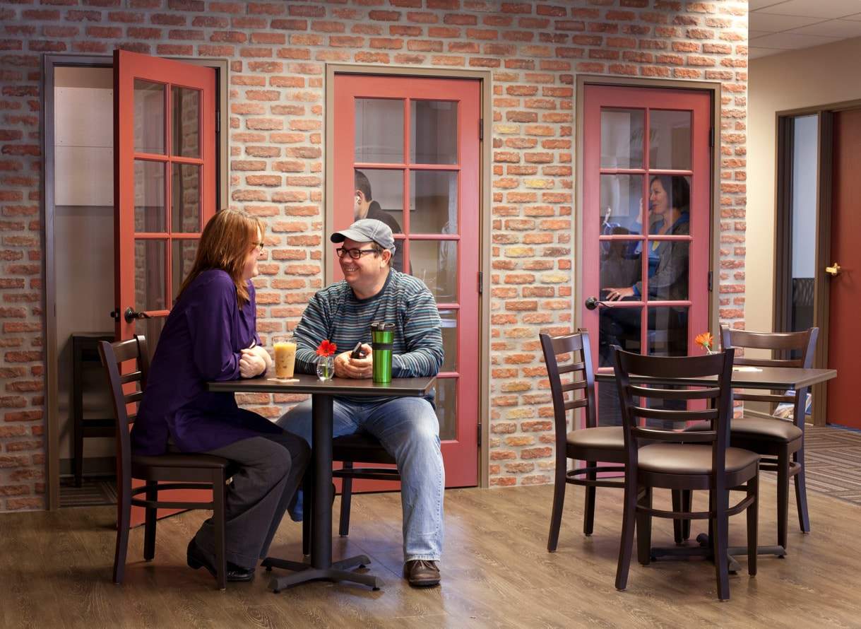 People sitting in coffee shop setting with individual booths with closed doors