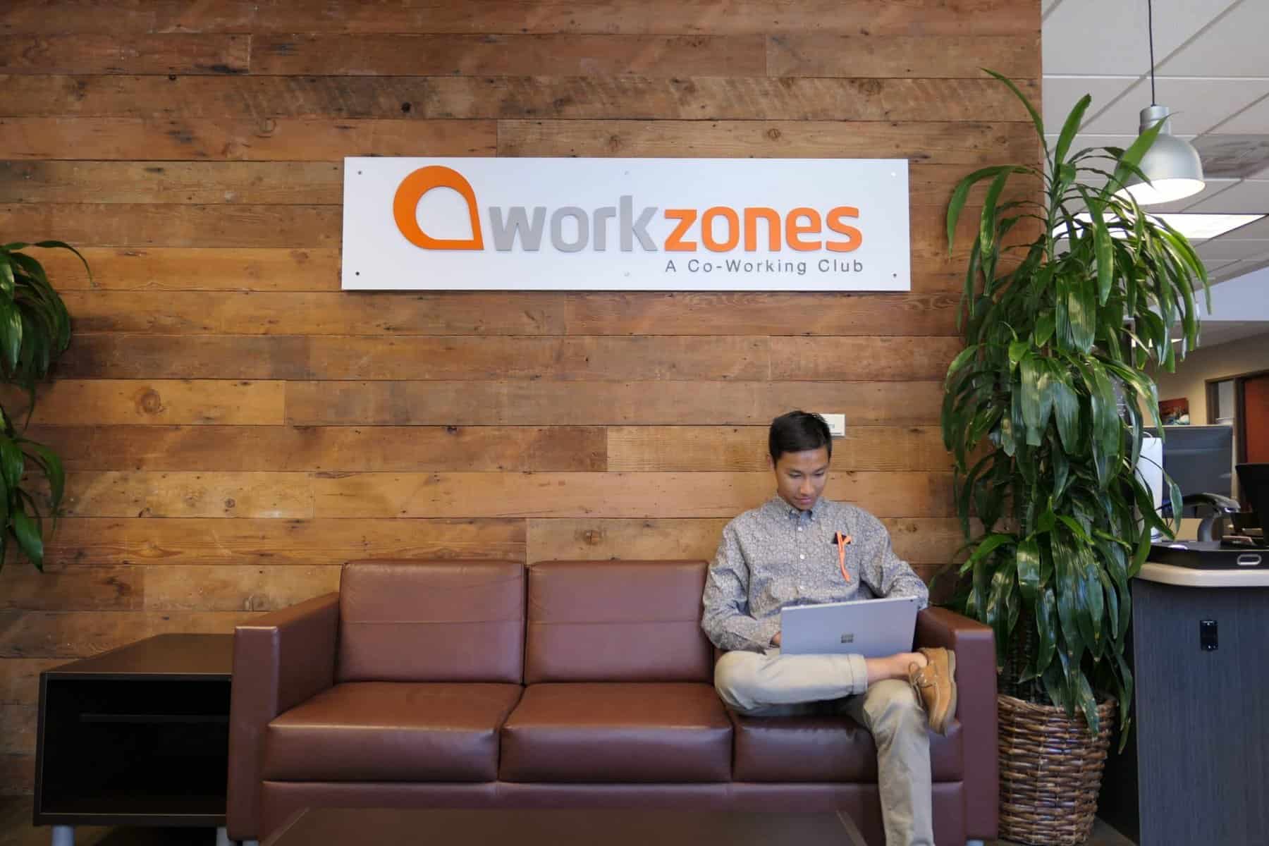 Person working on laptop below workzones sign
